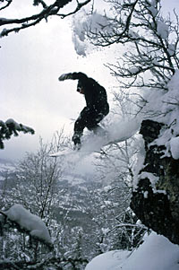 Snowboarder i vill fart utfor en knaus